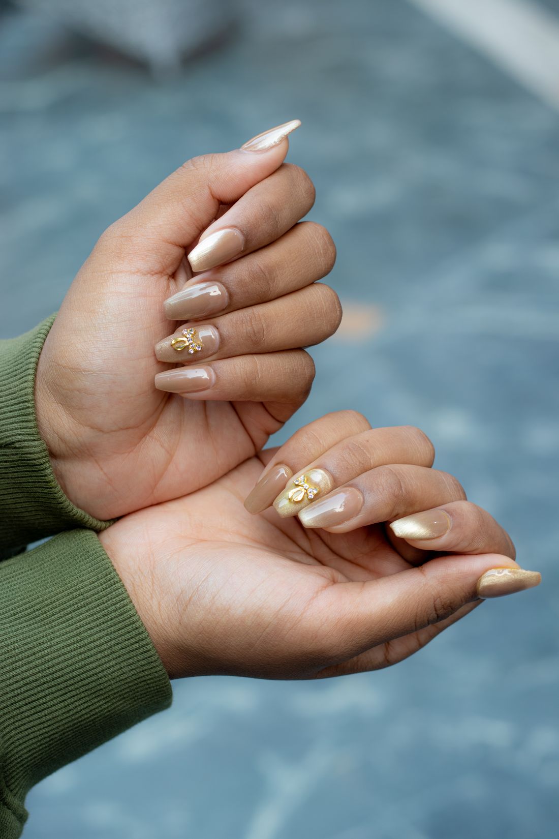 Handen met nude nagels met bladgoud en kleine gouden details